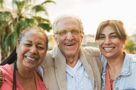Happy elderly people smiling on camera with city in background during fall time - Joyful senior friendship